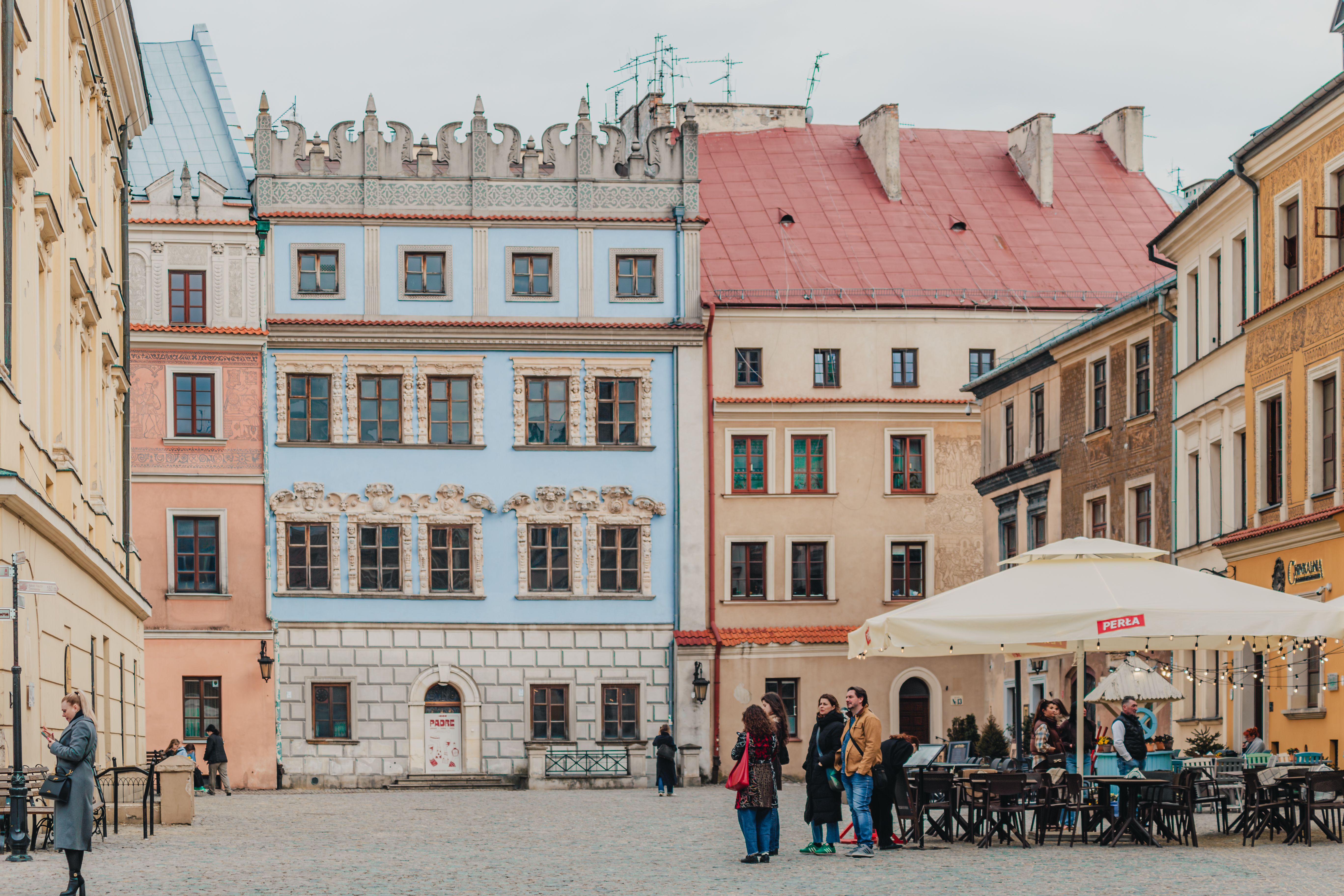 Lublin Old Town at golden hour with colorful Renaissance townhouses, Krakow Gate, and Market Square glowing in warm morning light