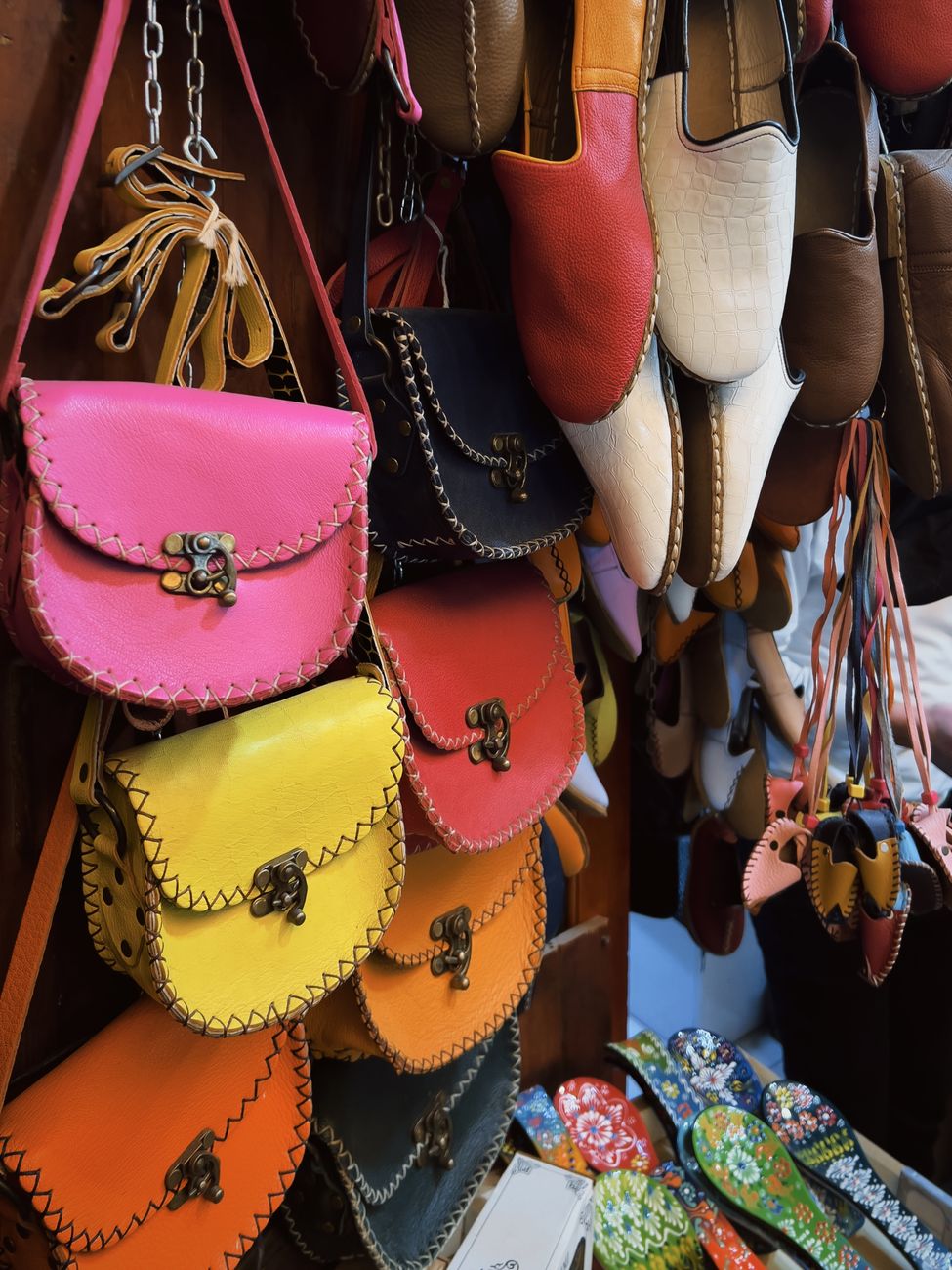 Leather handbags and traditional shoes displayed in a market setting