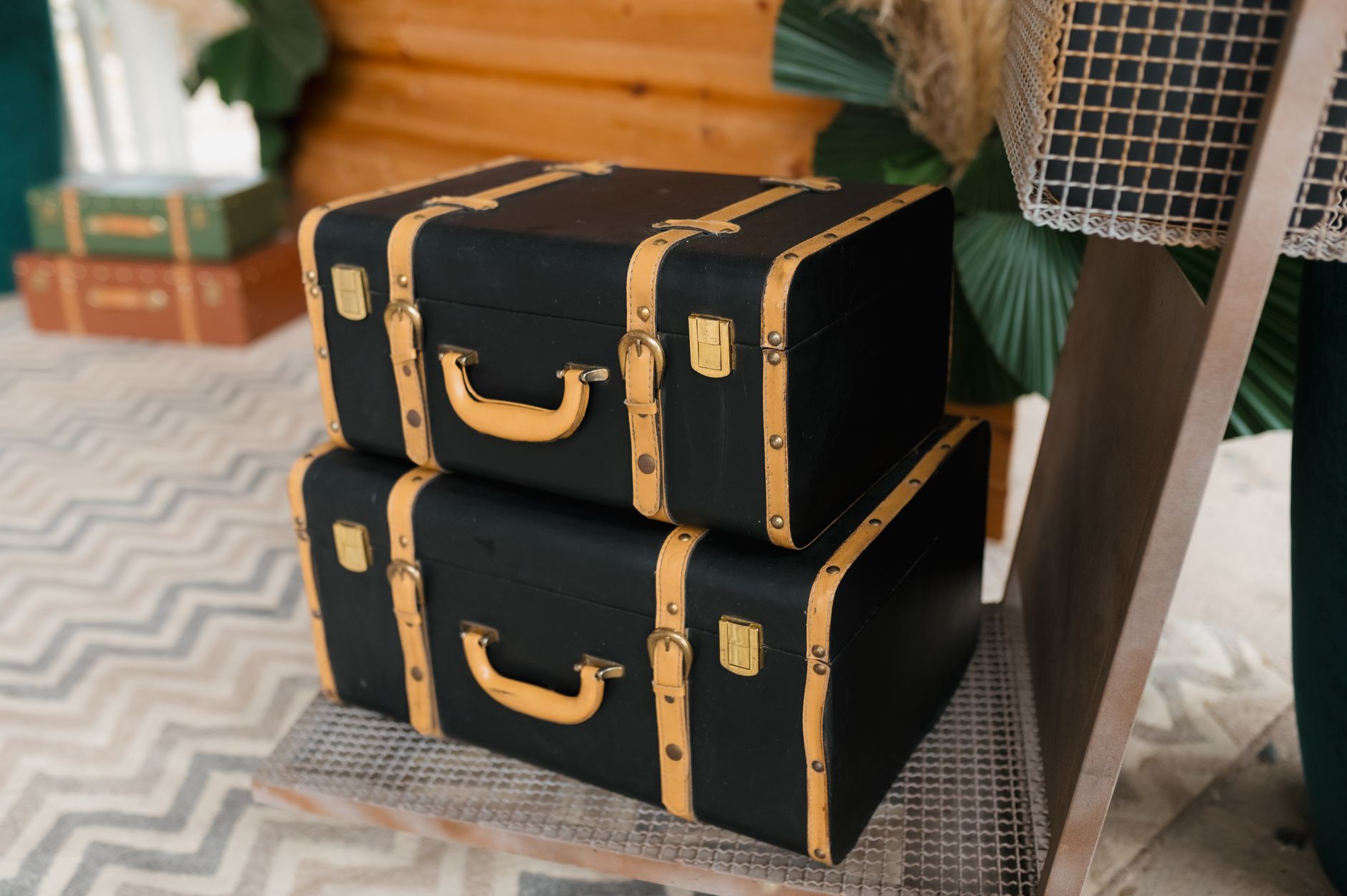 Stacked vintage black suitcases with tan straps create a nostalgic travel vibe.