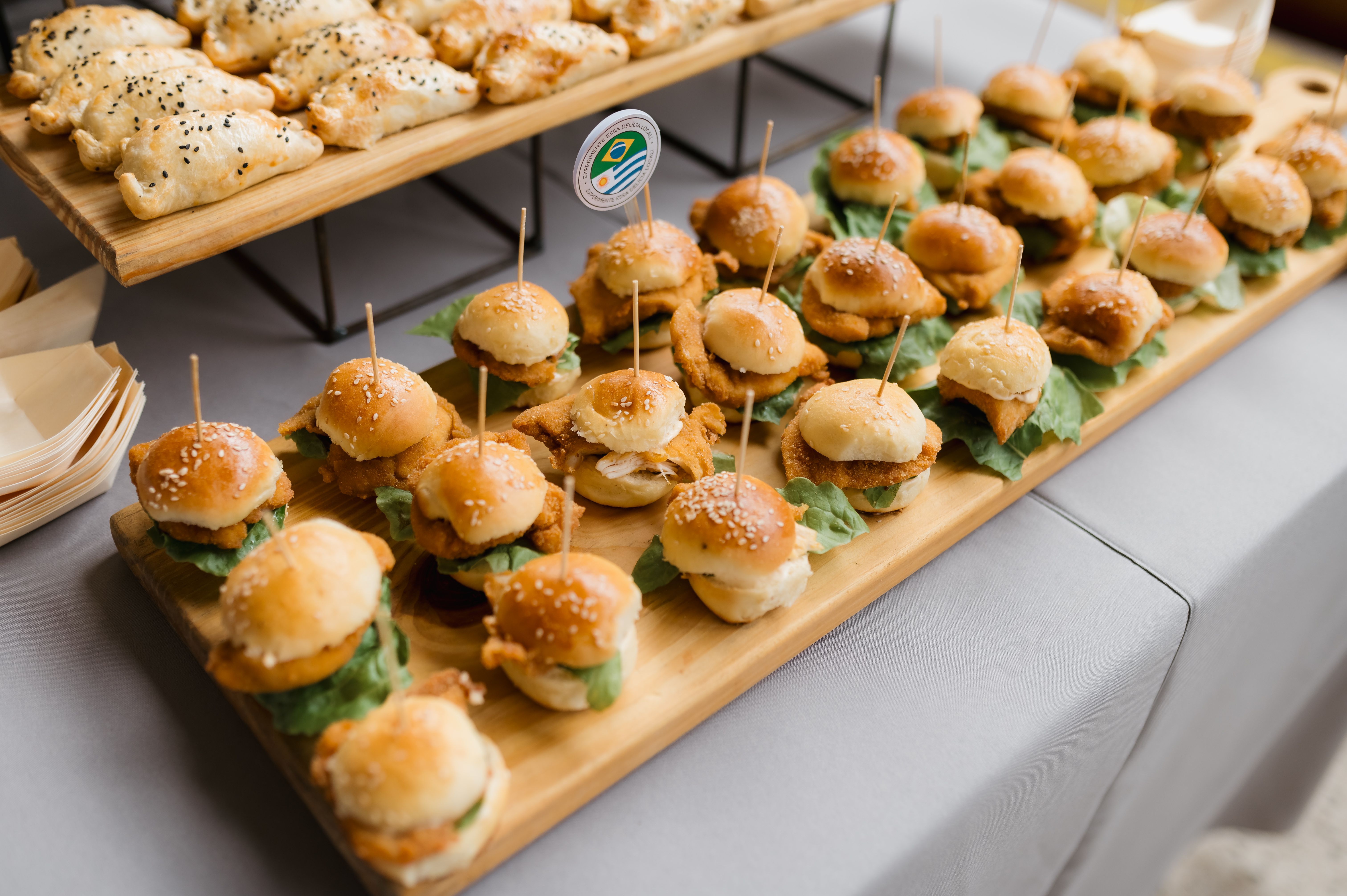 Tasty mini burgers and assorted pastries perfectly arranged on wooden board for a party.