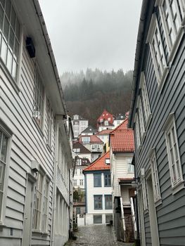 Explore the quaint alleyways and charming wooden houses in Bergen on a cloudy day.