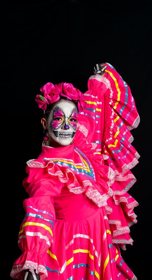 Free A person in a Catrina costume wearing traditional Mexican dress with colorful makeup and floral headdress. Stock Photo
