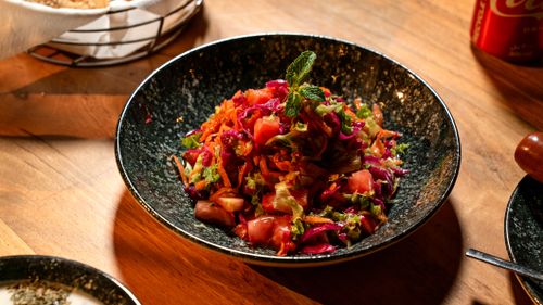 Free Vibrant vegetable salad with mint garnish in a rustic setting. Healthy and delicious. Stock Photo