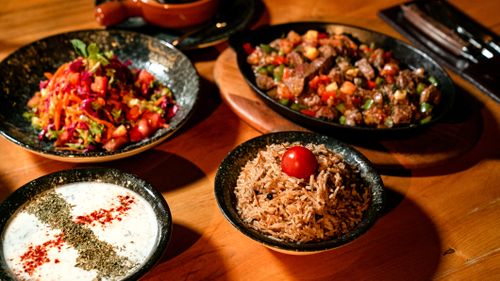Free Vibrant Mediterranean meal featuring rice, salad, stew, and yogurt sauce on wooden table. Stock Photo