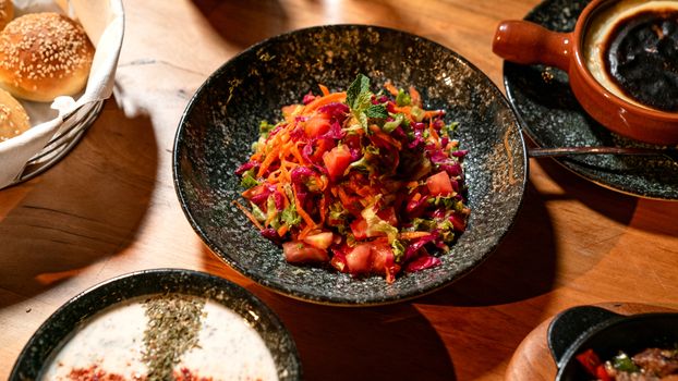 Colorful vegetable salad dish with bread rolls, ideal for healthy meals.