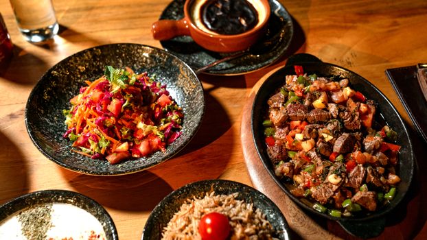 Vibrant Mediterranean dishes on a wooden table, featuring salads and grilled meat.