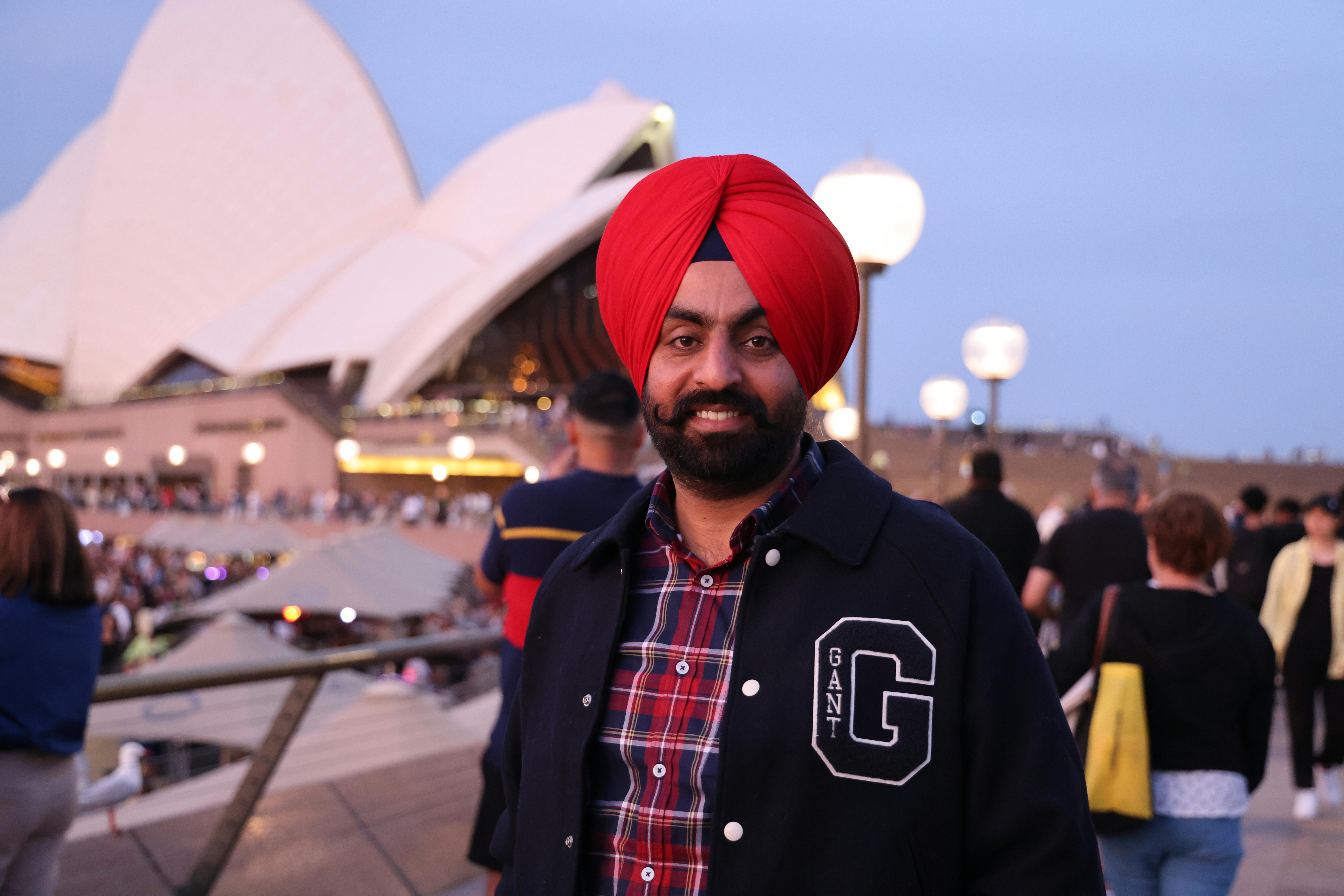 Portrait of a man in a red turban at Sydney Opera House during twilight.