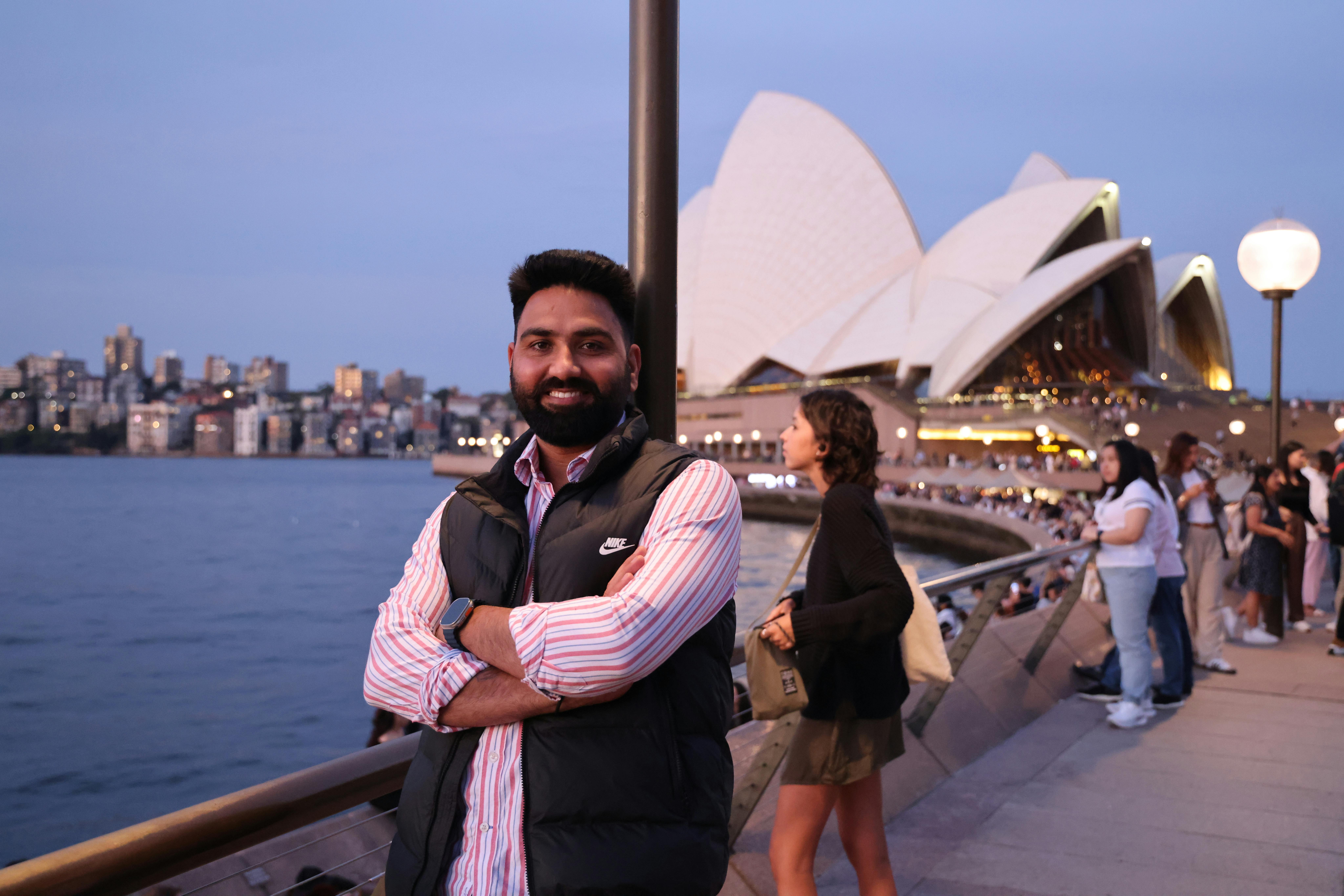 A man stands by the Sydney Opera House at dusk, offering a scenic backdrop.