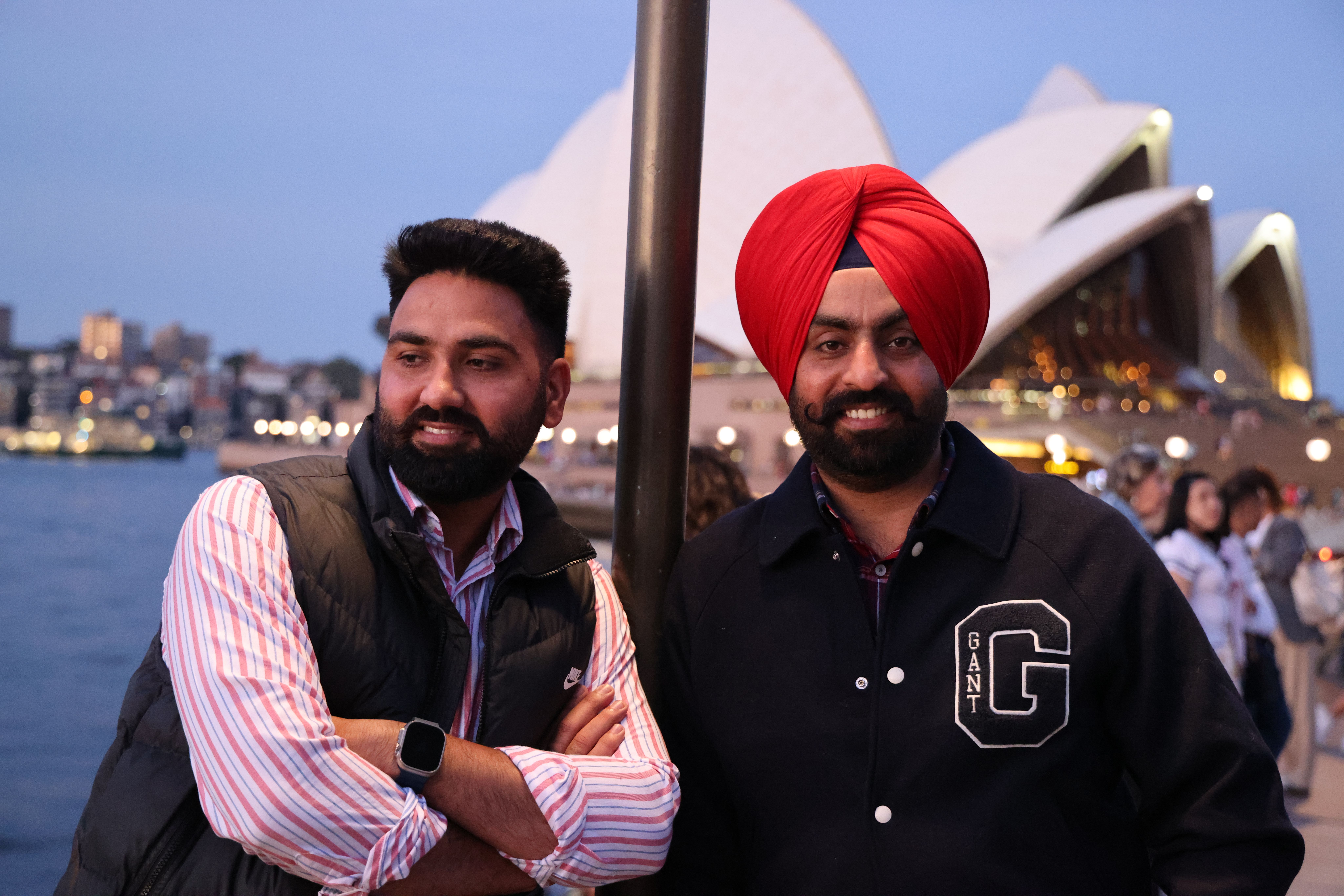 Two friends posing in front of the Sydney Opera House at twilight, enjoying the city views.