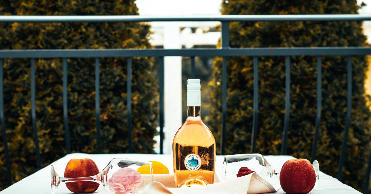 Rosé wine bottle and fruits on a table outdoors creating a relaxed vibe.