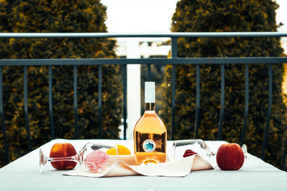 Sticlă de vin rosé rece și fructe pe o masă în aer liber