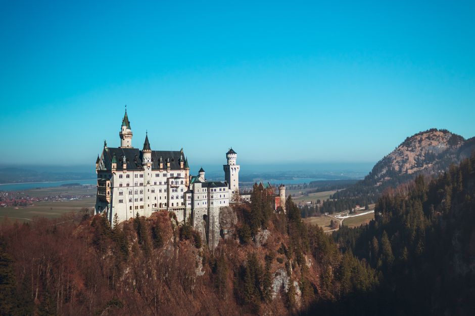 Breathtaking aerial view of Neuschwanstein Castle against a clear blue sky in Schwangau, Germany.