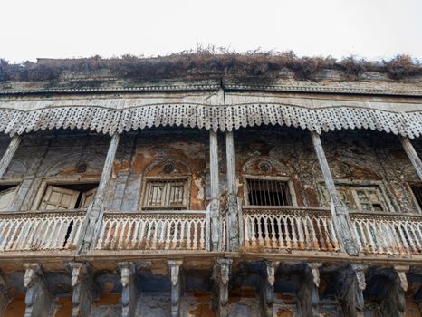 Detailed view of a weathered historical building facade with ornate architectural elements and signs of decay.