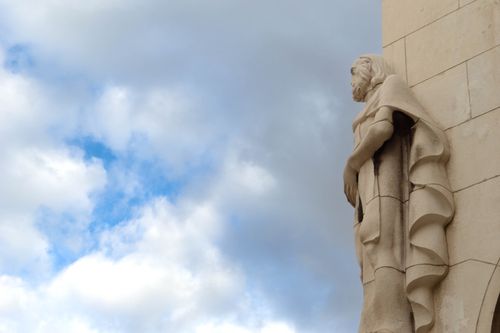 Free A majestic stone statue stands against a backdrop of blue sky and clouds. Stock Photo