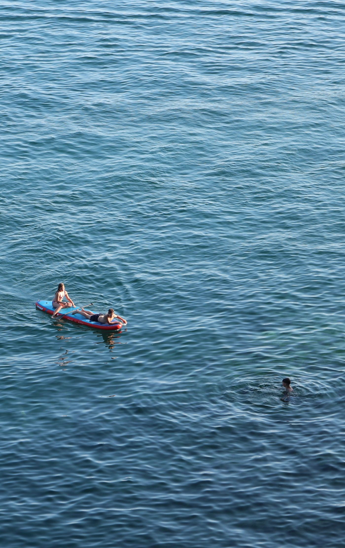 Two people paddleboarding across calm open sea