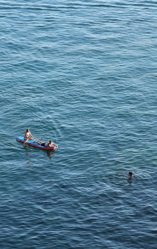 Free Two people paddleboarding on clear ocean waters with serene surroundings. Stock Photo