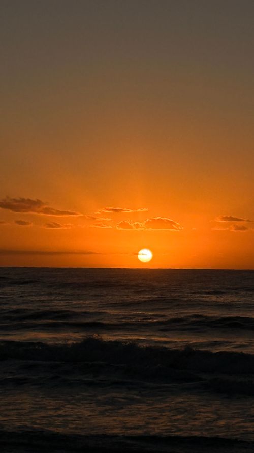 Free A stunning sunset over the ocean in Uruguay with vibrant orange hues and tranquil waves. Stock Photo