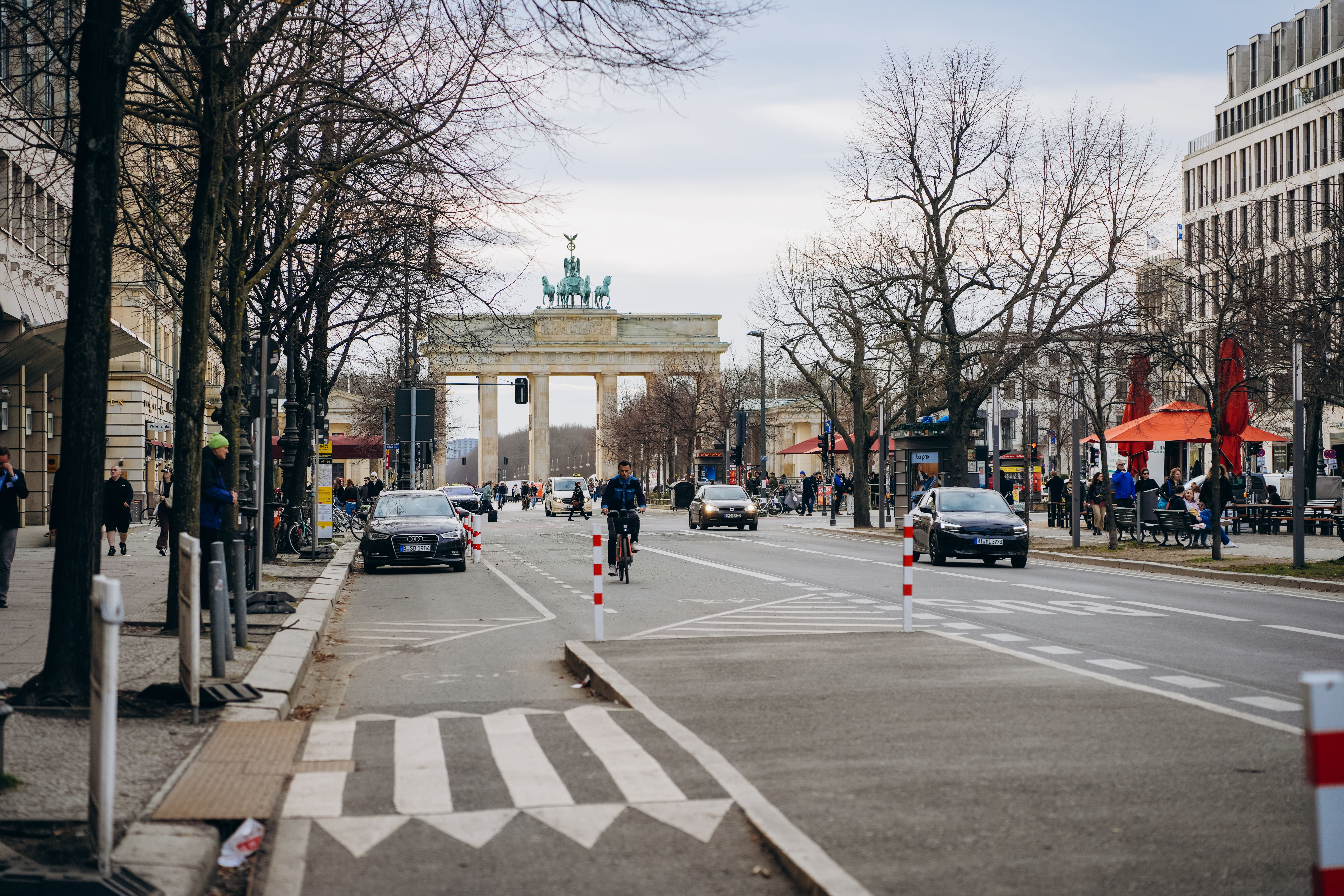 Street scene with Brandenburg Gate in Berlin, showcasing urban life and historic architecture.