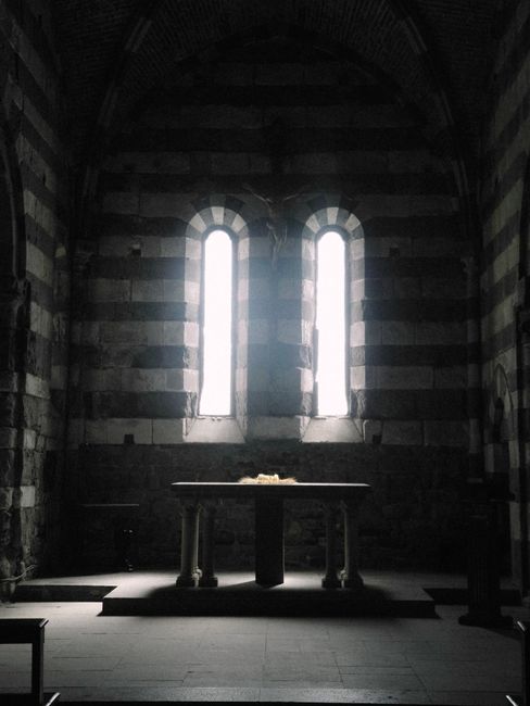 Fotomural Interior sombrío de una iglesia histórica con la luz del sol entrando a raudales por las ventanas góticas e iluminando el altar.