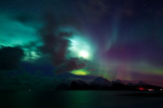Stunning display of Aurora Borealis illuminating snow-capped mountains in Nordland, Norway.