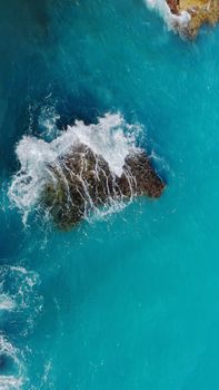 Aerial view of turquoise waves crashing on rocks in Antalya, Türkiye's stunning coastline.
