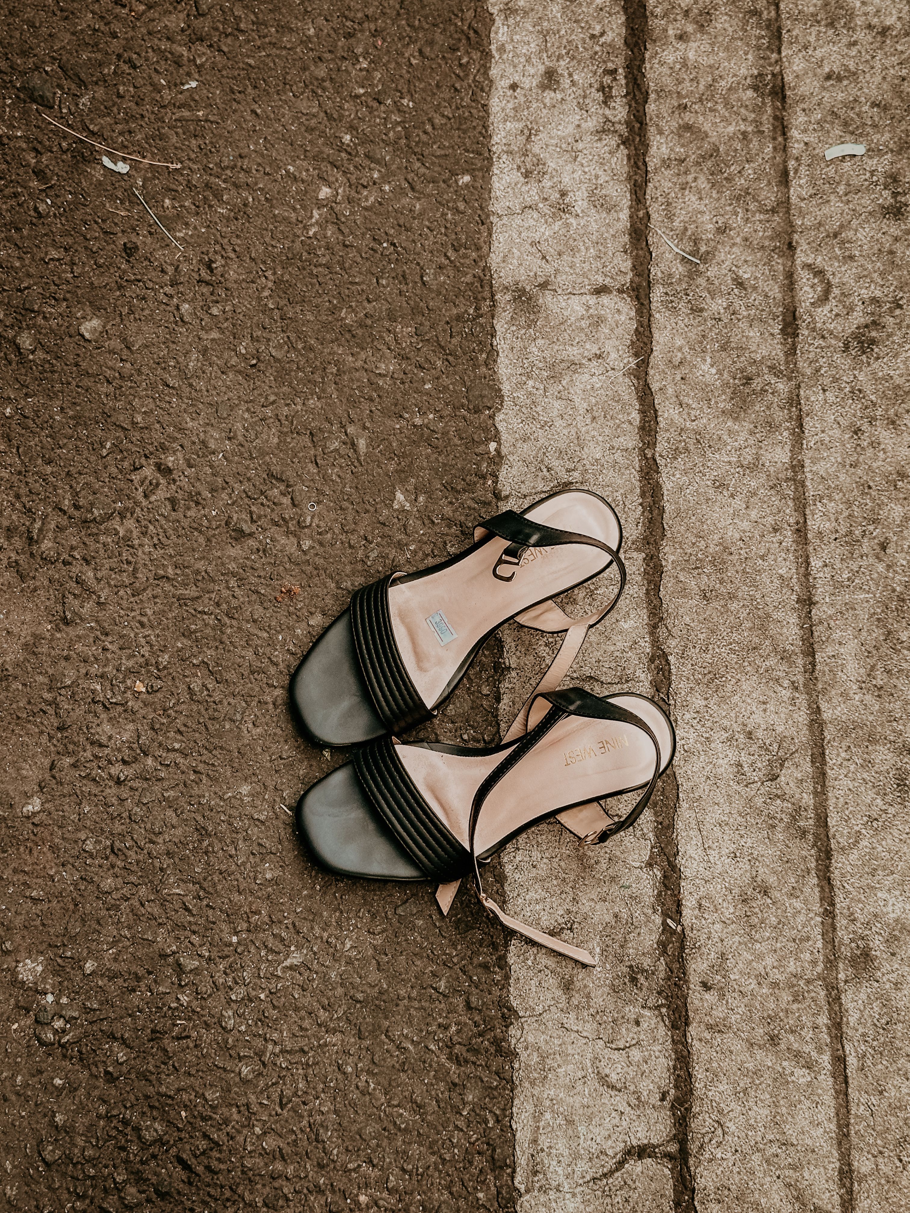 Black sandals on concrete provide an urban contrast in this textured street composition.