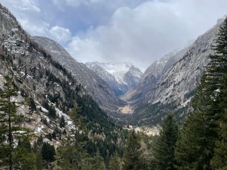 Breathtaking view of Val Masino mountains with snow-capped peaks and lush pine trees.