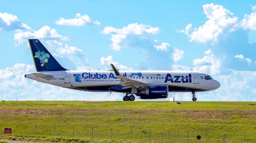 Free Azul Airlines aircraft taxiing on the runway under a bright blue sky. Stock Photo