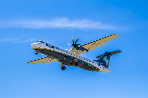 Free A commercial propeller plane mid-flight under a clear blue sky, showcasing aviation prowess. Stock Photo