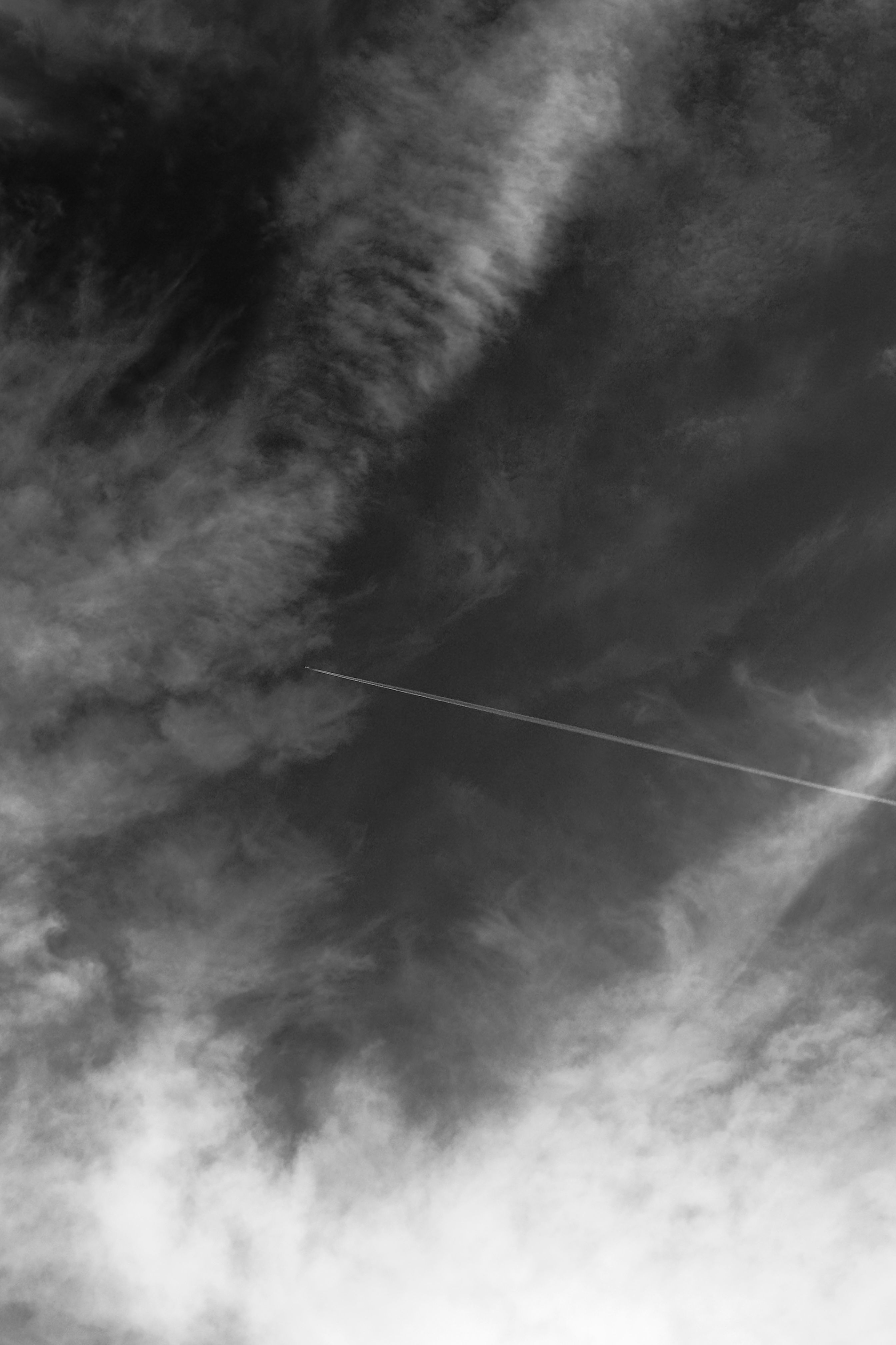 Black and White Cloudy Sky with Contrail · Free Stock Photo