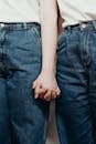 一对穿着牛仔裤的情侣牵手亲密特写，象征着爱与联系