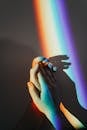 Artistic representation of unity with hands holding under colorful rainbow light reflection.