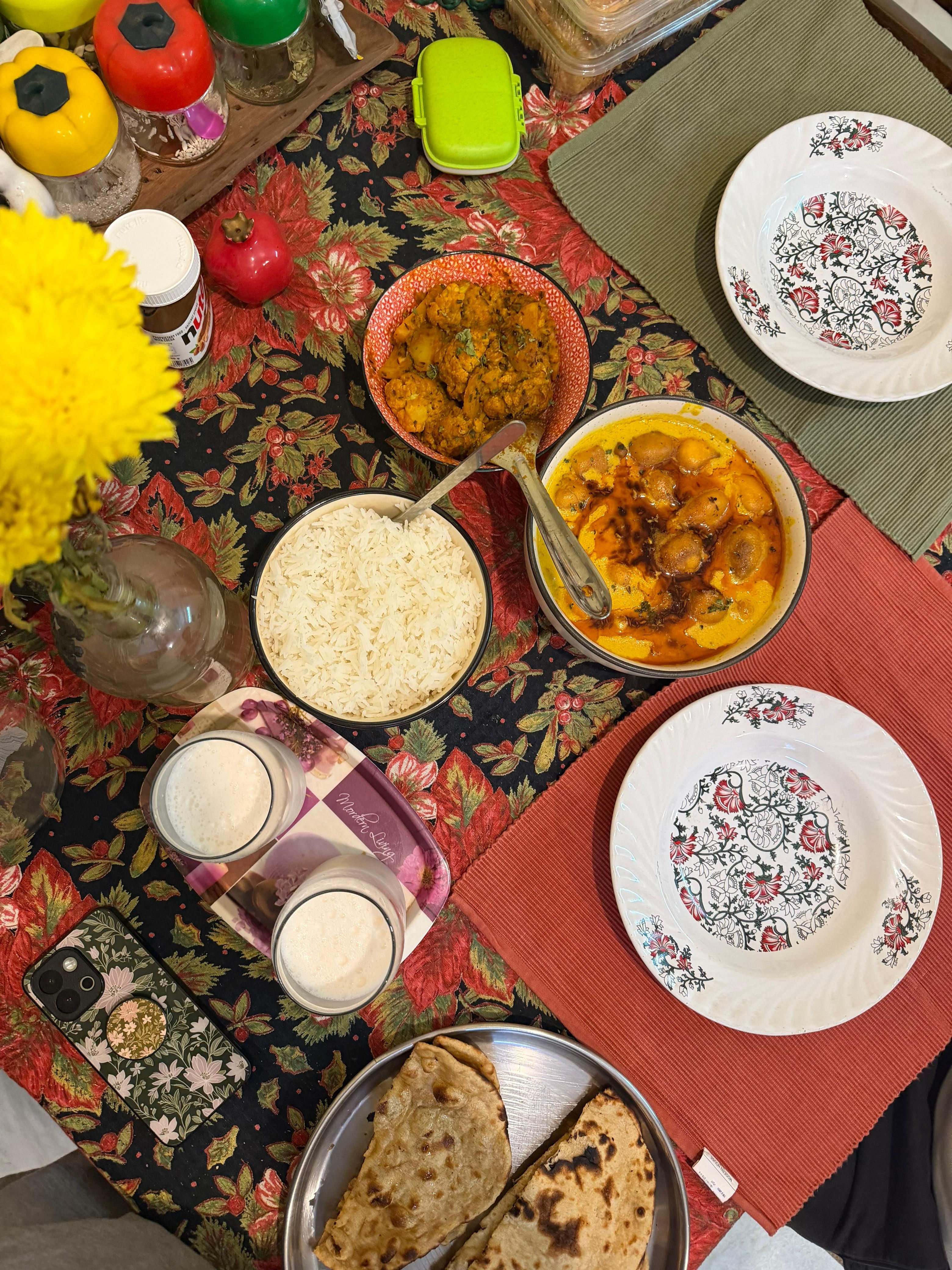 Colorful Indian meal setup with rice, curry, and flatbread on a decorated table.