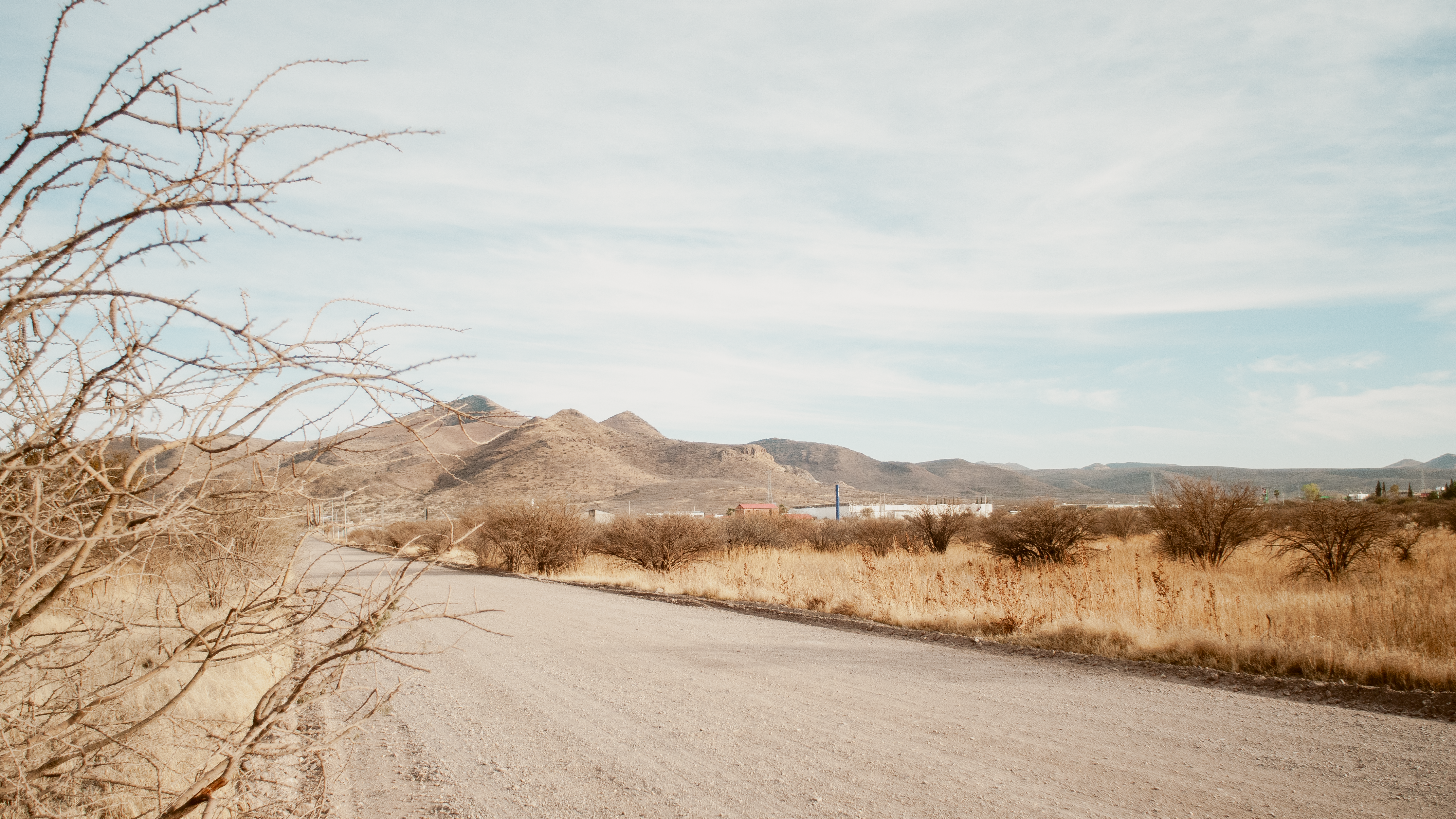 A serene desert landscape with mountains, a dirt road, and a clear blue sky, perfect for travel themes.