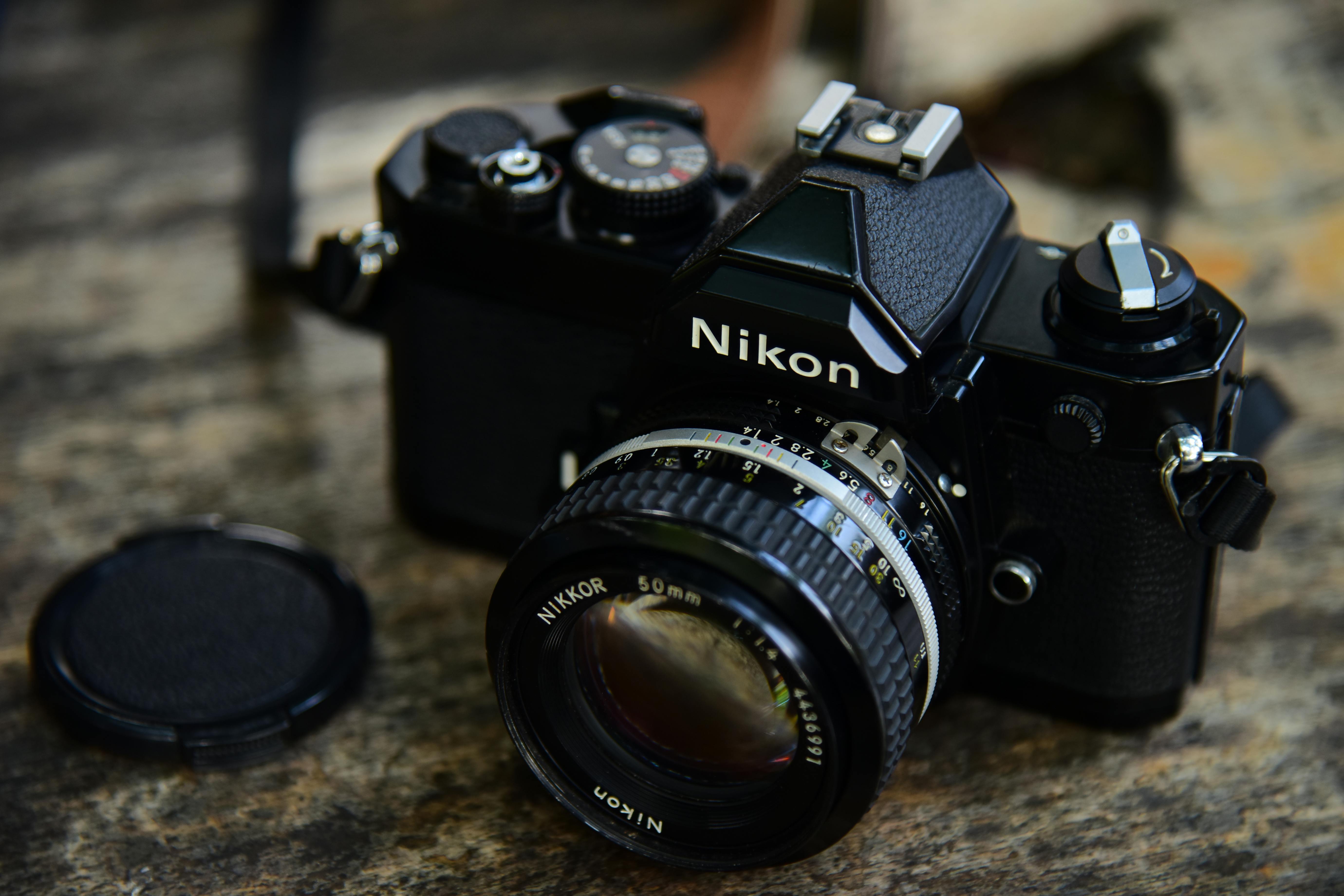 Close-up of a classic Nikon film camera on a rustic wooden table.