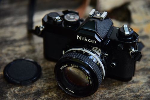 Free Close-up of a classic Nikon film camera on a rustic wooden table. Stock Photo