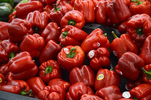 Free A vibrant pile of fresh red bell peppers in a market setting, ideal for food and lifestyle themes. Stock Photo