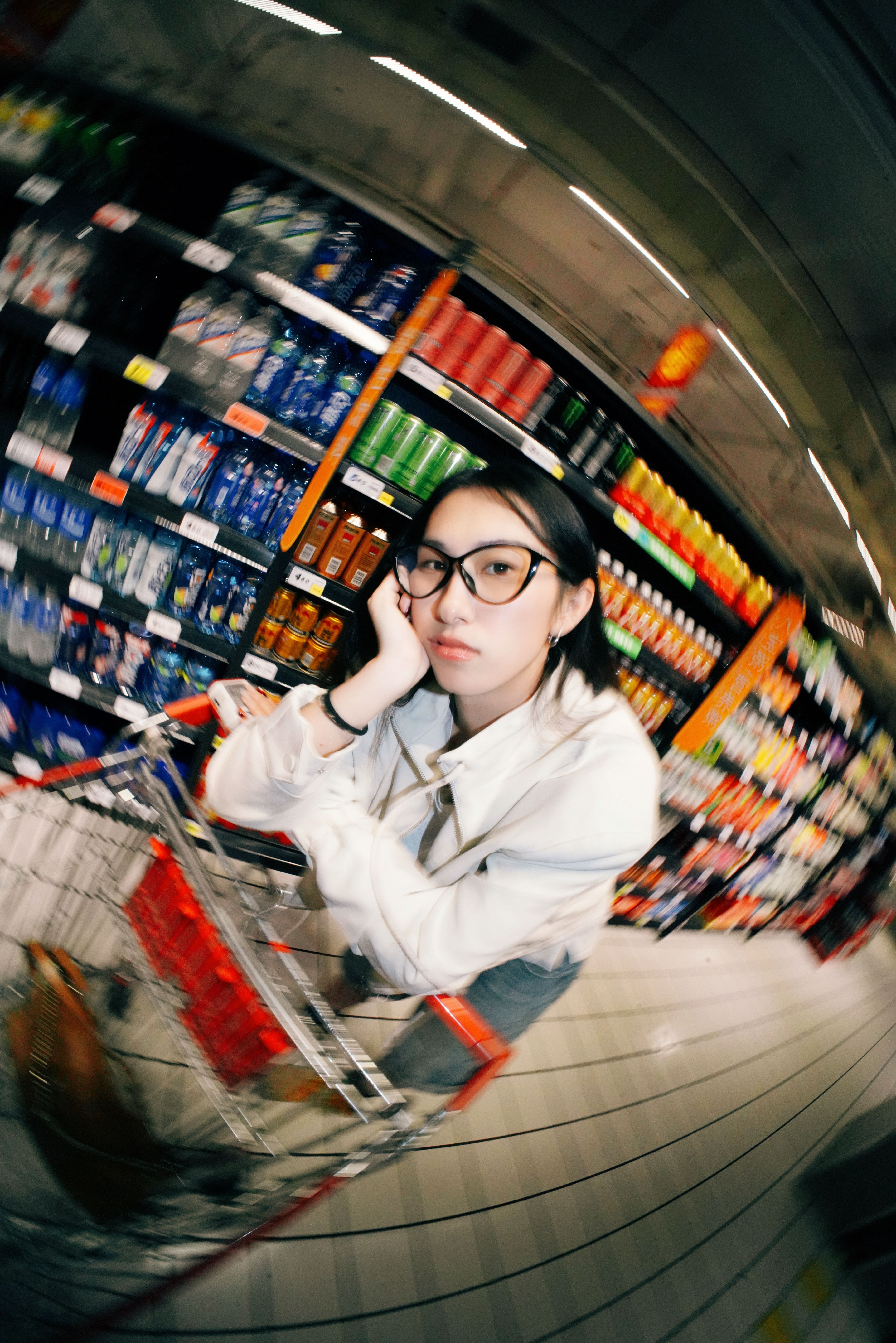Young woman leaning on a shopping cart in a grocery aisle, surrounded by colorful products.