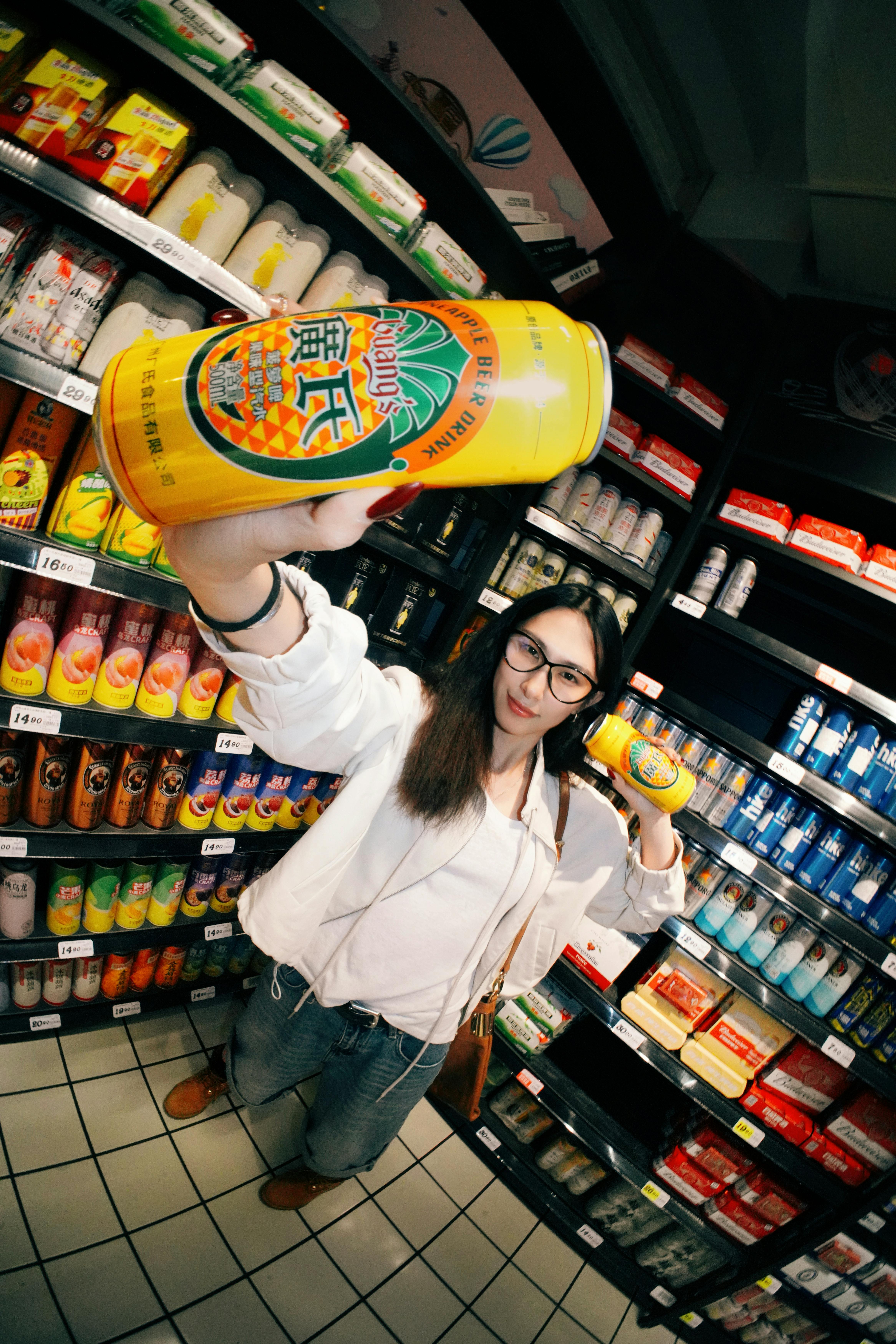 Woman showcasing a drink in an Asian supermarket aisle. Bright and vibrant.
