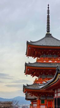 A detailed view of the ornate architecture of a traditional Japanese pagoda on a cloudy day