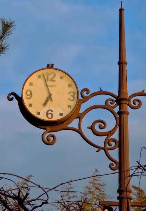 Free Ornate vintage street clock on a pole against a clear blue sky backdrop. Stock Photo