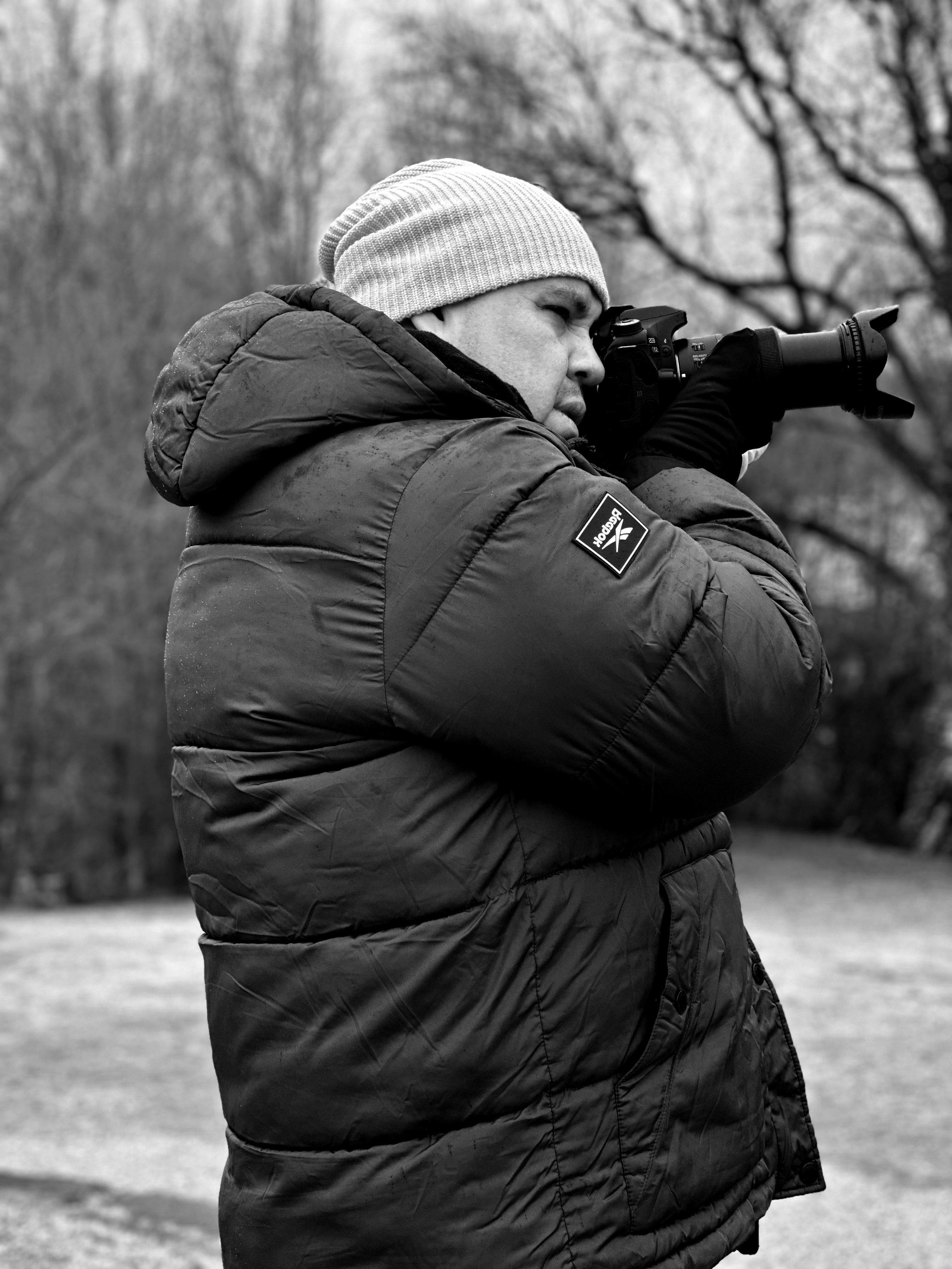 A photographer in winter attire capturing outdoor scenes in Bolzano, Italy.