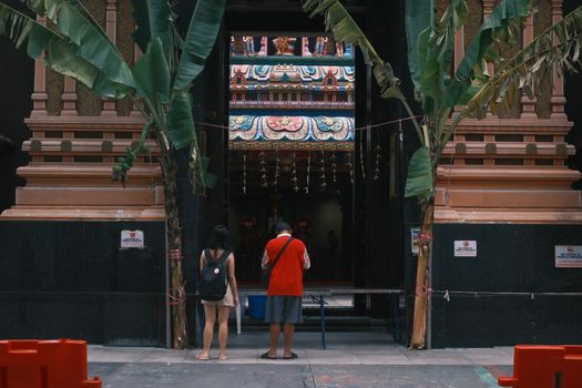 Visitors standing at the ornate entrance of a temple in Melaka, Malaysia.
