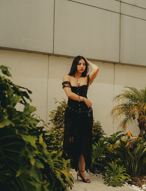Free Stylish woman in black dress posing among tropical plants in an urban environment. Stock Photo
