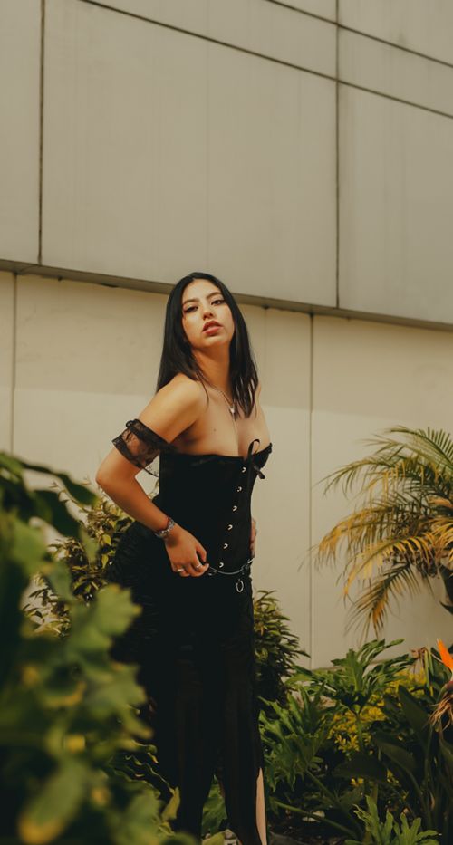 Free Stylish woman in black corset posing in an urban garden. Fashion and nature blend. Stock Photo