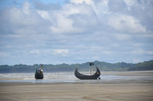 Free Traditional wooden boats on the vast sandy beach of Cox's Bazar, under a cloudy sky. Stock Photo