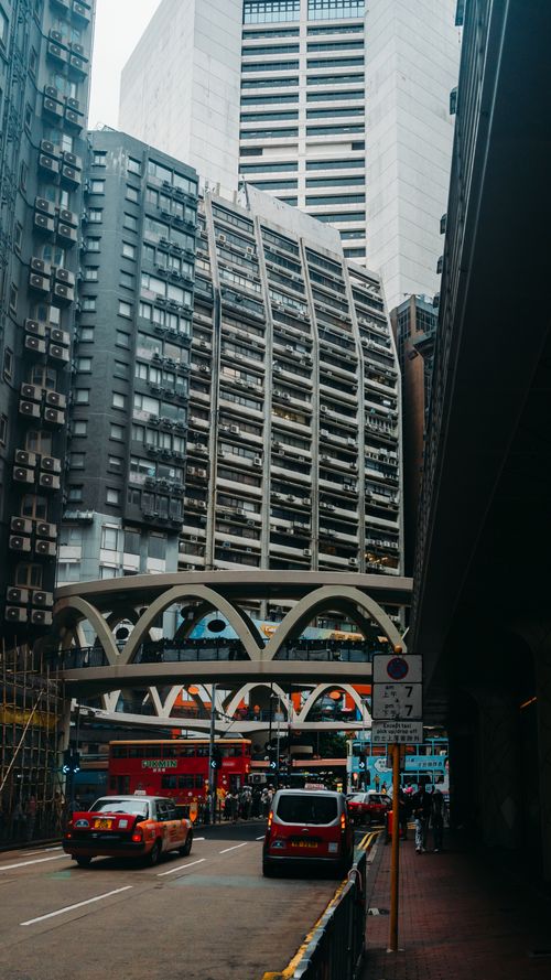 Free Vibrant city street with towering buildings and a distinctive arched overpass. Stock Photo