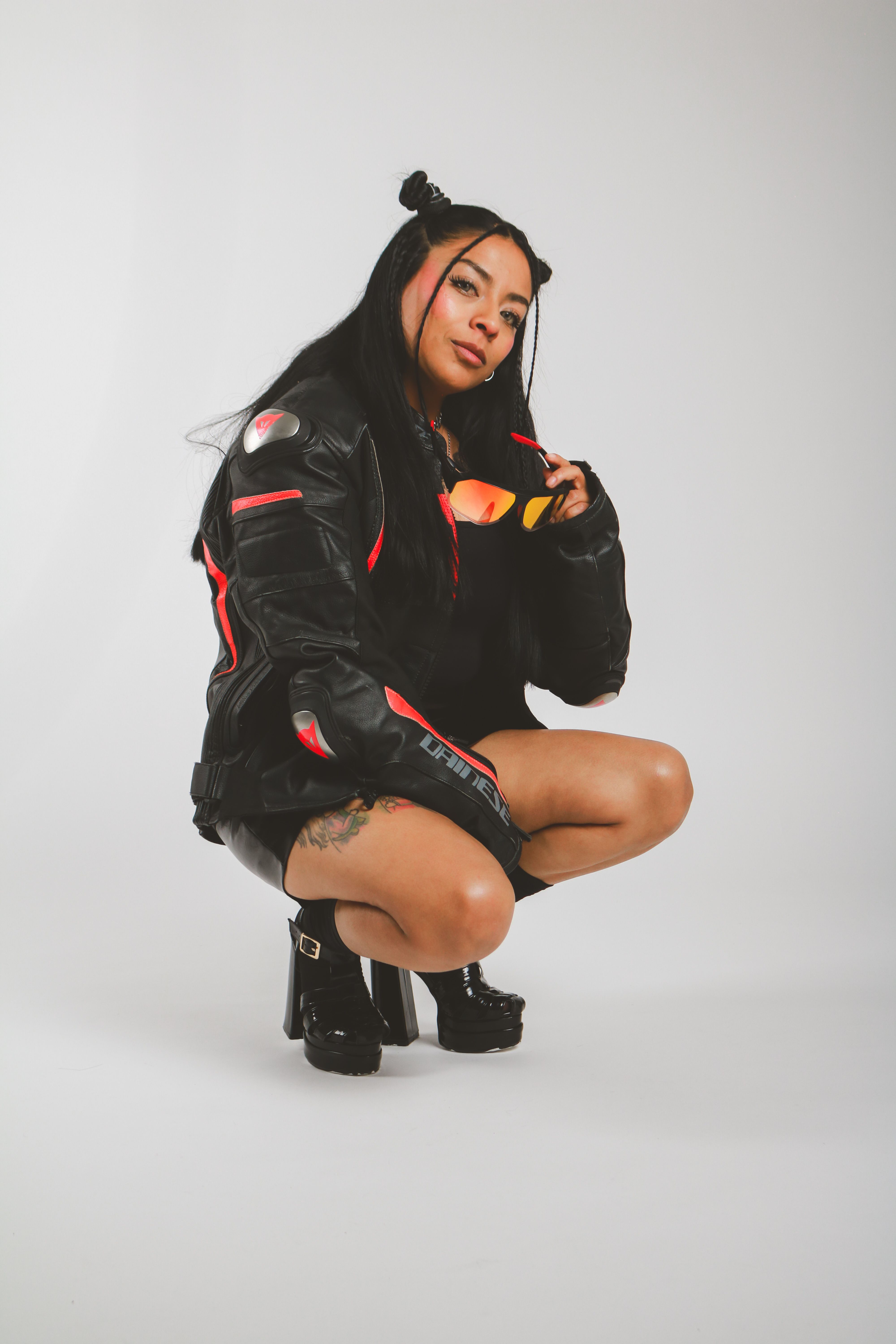 Woman in black leather outfit with bold, edgy style located indoors.