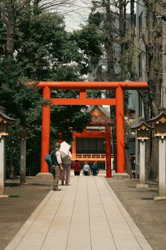 Visitors walk through a traditional wooden torii gate at a Shinto shrine in Tokyo, Japan.