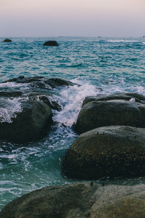 Free Dramatic view of ocean waves crashing over rocks at sunset, illustrating nature's power and beauty. Stock Photo